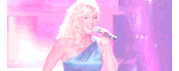 a woman singing into a microphone in a blue dress