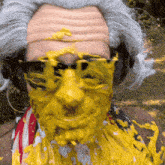 a man wearing a wig and sunglasses is covered in yellow paint