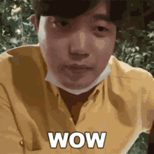 a man wearing a mask and a yellow shirt is making a surprised face .