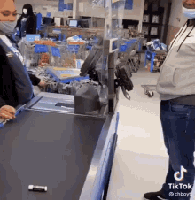 a woman wearing a mask is standing at a check out counter in a store .