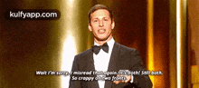 a man in a suit and bow tie is giving a speech and says wait i 'm sorry i misread that again
