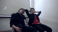 two men are sitting next to each other with their arms behind their heads