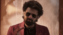 a man with a beard wearing sunglasses and a pink jacket
