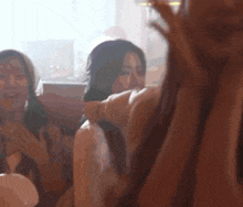 a group of women are sitting in a room with their hands up
