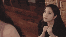 a woman is pointing at her face while another woman looks on