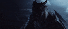 a dragon with wings is standing in the dark with a cloudy sky in the background