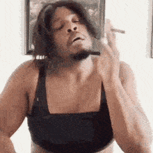 a man wearing a bra is smoking a cigarette .
