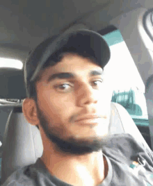 a man with a beard is sitting in the back seat of a car wearing a hat .