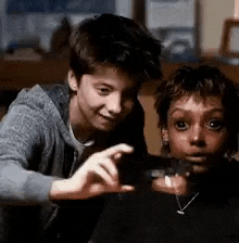 a boy and a girl are sitting next to each other and taking a picture of themselves .