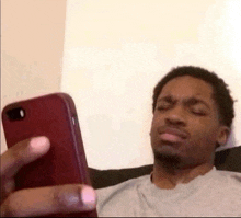 a man is sitting on a couch looking at his phone and making a funny face .