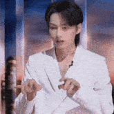 a man in a white suit is making a gesture with his hands .