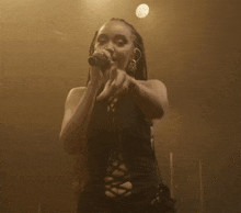 a woman singing into a microphone on stage in a dark room