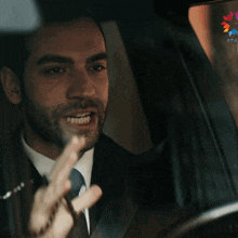 a man wearing a suit and tie is driving a car