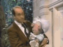 a man in a suit is holding a monkey in his arms .