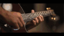 a close up of a person playing an acoustic guitar with a blurred background