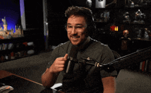a man giving a thumbs up in front of a microphone with the words two thumbs up behind him