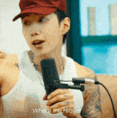 a man wearing a red hat is holding a microphone with the words where the real at at the bottom