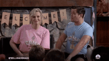 a man and a woman are sitting in front of a banner that says welcome !