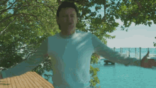 a man is standing on a dock with his arms outstretched in front of a body of water