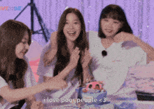a group of girls are sitting around a cake and one of them is saying i love poor people < 3