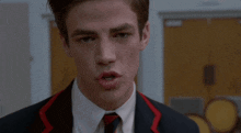 a young man in a suit and tie with a red stripe