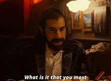 a man with a beard is sitting at a table with a plate of food and says what is it that you most