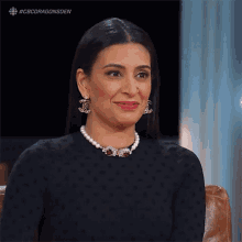 a woman wearing a pearl necklace and earrings smiles