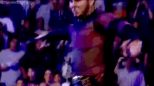 a man in a purple sweater is standing in front of a crowd of people .