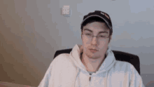 a man wearing a hat and glasses is sitting at a desk