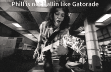 a black and white photo of a man playing a guitar with a caption that says phil is not ballin like gatorade