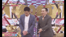 a man in a suit and tie stands next to another man in a suit and tie on a stage