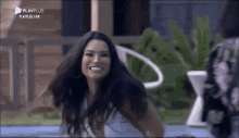 a woman is standing next to a pool smiling .