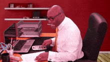 a man sitting at a desk with a laptop and a calculator in front of him