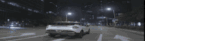 a car is driving down a road at night .