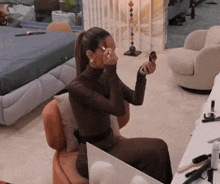a woman sits in a chair applying makeup to her face