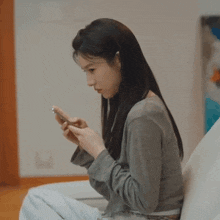 a woman is sitting on a couch looking at her cell phone