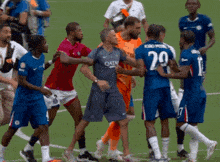 a soccer player wearing a qatar shirt is surrounded by other players