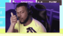 a man in a yellow shirt is wearing headphones and giving a thumbs up .