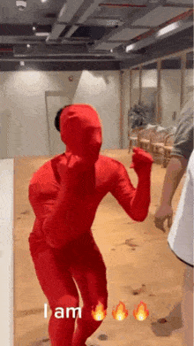a person in a red bodysuit is dancing in a room with fire signs behind them .