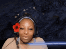 a woman wearing headphones and a flower in her hair is smiling