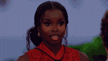 a woman wearing a red top and gold earrings looks at the camera