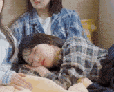 a girl in a plaid shirt is sleeping on a bed next to two other girls