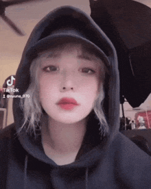 a girl wearing a hoodie and a hat has a tiktok icon on her screen