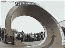 a skateboarder is doing a trick on a cardboard ring while a crowd watches .