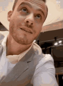 a man with a beard wearing a suit and white shirt is looking up .