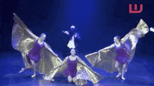 a group of dancers are performing on a stage with wings .