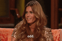a woman with long hair is sitting on a couch and saying odd