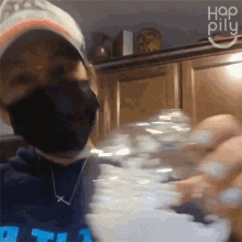 a person wearing a mask and a hat is holding a bottle of water