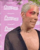 a man with red paint on his face is standing in front of a purple wall with the word dare on it