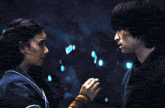a man and a woman are touching each other 's faces in a dark room